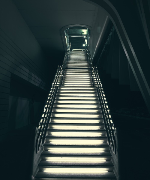 A vertical shot of industrial modern grey stone stairs illuminated with lights leading up. Perfect for an urban industrial scenario.